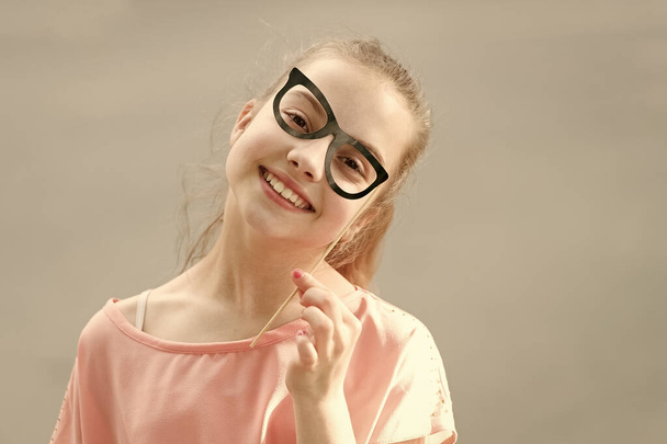 She is radiating happiness. Small smiling girl with funny look through prop glasses. Happy little child with adorable face shining with happiness. Children bring so much happiness. Happiness concept - Photo, Image