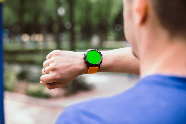 Muž se dívá na svůj smartwatch se zelenou chromakey obrazovkou - Fotografie, Obrázek