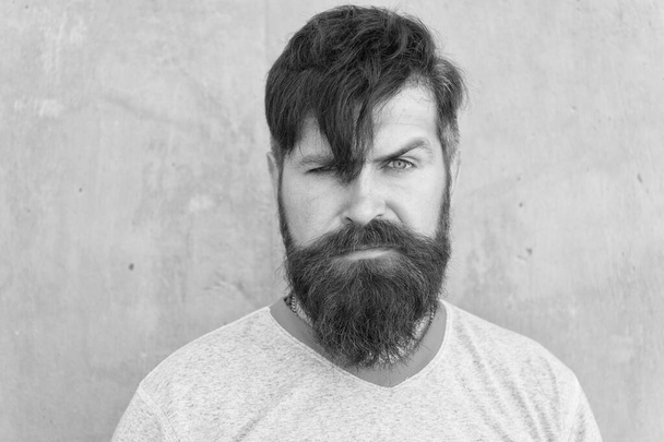 The bushy mustache is great. Bearded man with stylish mustache shape. Brutal hipster with textured mustache hair on unshaven face. Serious guy wearing long beard and mustache on grey wall - Foto, Imagem