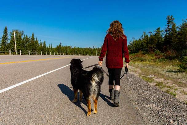 Señora caminando por la carretera con su perro
 - Foto, imagen