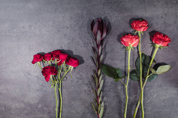 A variety of beautiful flowers lying on a grey table. Flower delivery. The job of a florist - 写真・画像