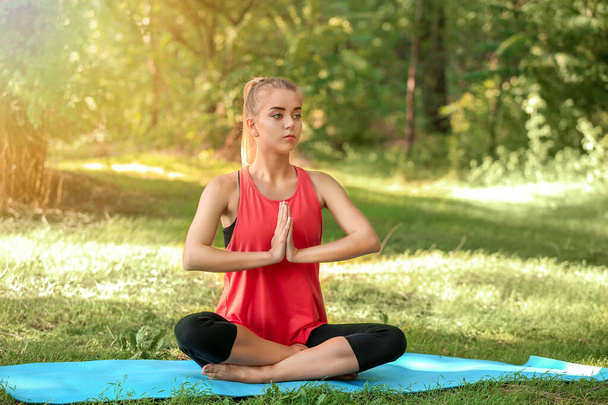 Beautiful young woman practicing yoga in park - 写真・画像