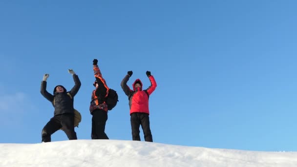 Tourists met on top of success. Alaskan travelers go to the top of a snowy hill and rejoice in victory against a winter sunset. team work of people. business teamwork, victory and success. - Footage, Video