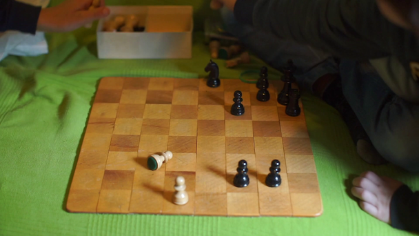 Las manos de los niños ponen piezas de ajedrez en una caja
 - Metraje, vídeo