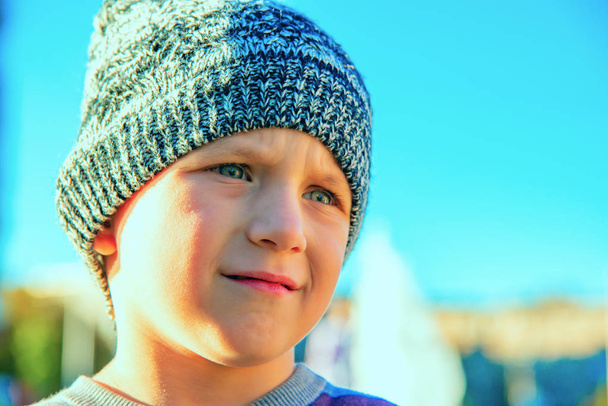 Retrato de un niño triste y triste en un sombrero de punto gris
. - Foto, imagen