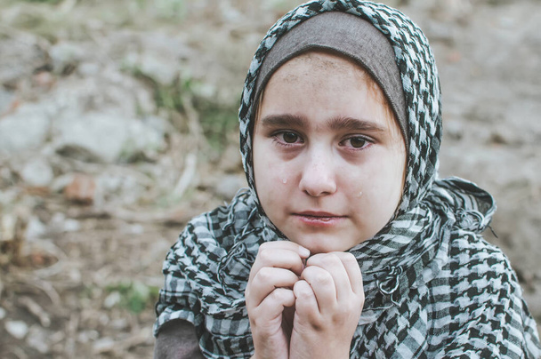 戦争中の難民の子供、遺跡に汚い顔を持つイスラム教徒の少女、平和と戦争の概念、子供が泣いて助けを待っている. - 写真・画像