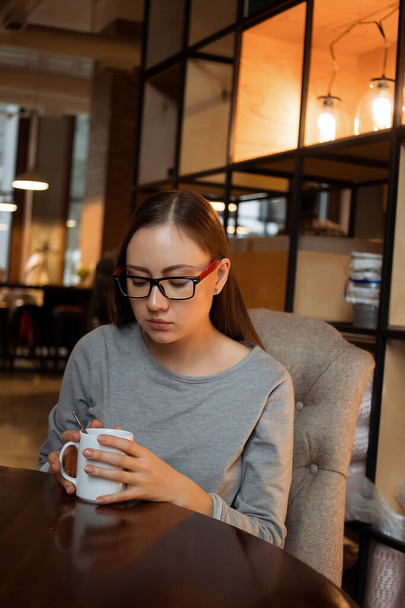 Женщина, мешающая горячий напиток в кафе
 - Фото, изображение