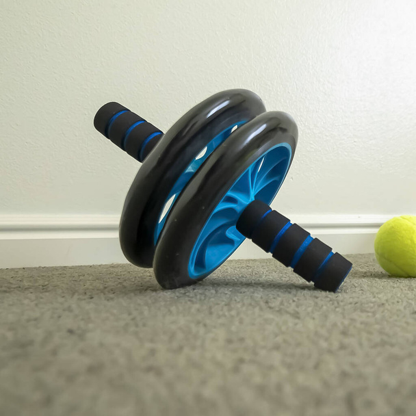 Quadrado Fechar de uma roda ab e empurrar para cima bar no chão de uma sala de fitness treino
 - Foto, Imagem