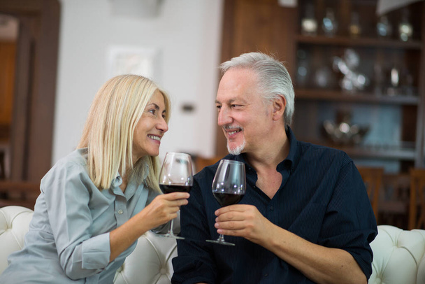 Mature couple enjoying a good red wine at home - Fotoğraf, Görsel