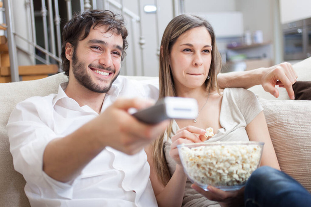 Young couple eating popcorn while watching a movie - Foto, Imagem