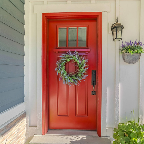 Красная входная дверь современного дома с зеленым венком
 - Фото, изображение