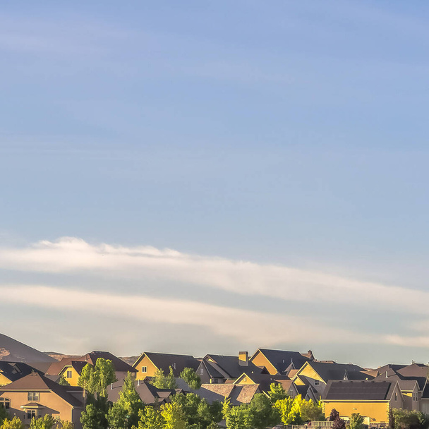 Vierkante frame Zonnige dag uitzicht op huizen in een buurt met berg en blauwe lucht achtergrond - Foto, afbeelding