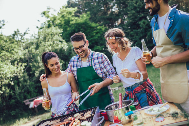 Giovani amici si divertono a grigliare carne godendo di festa barbecue
. - Foto, immagini