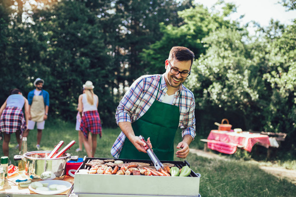 Young handsome man preparing barbecue for friends. - Photo, Image
