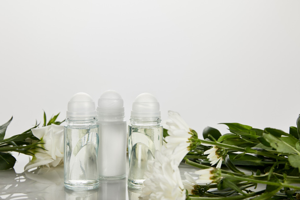 рулон на бутылках дезодоранта с цветами изолированы на белом
 - Фото, изображение