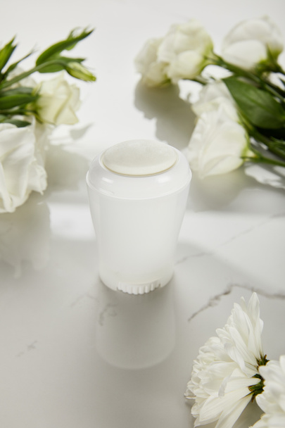selective focus of roll on bottle of deodorant with flowers on white surface - Foto, Bild