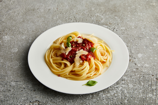 tasty bolognese pasta with tomato sauce and Parmesan on white plate on grey background - Foto, Imagen