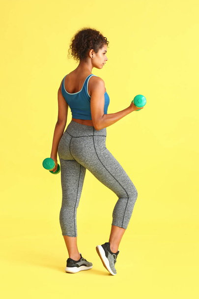 Sporty African-American woman with dumbbells on color background - Fotó, kép