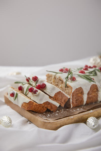 traditional Christmas cake with cranberry on wooden board near silver baubles isolated on grey - Foto, afbeelding