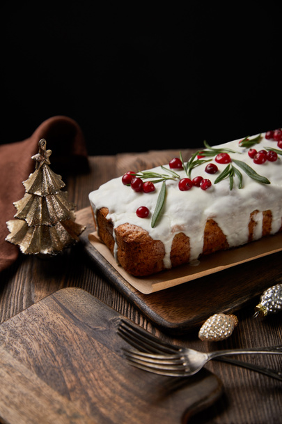 torta di Natale tradizionale con mirtillo vicino a bagattelle, forchette e tovagliolo marrone su tavolo di legno isolato su nero
 - Foto, immagini