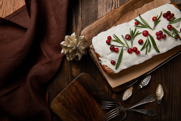top view of traditional Christmas cake with cranberry near baubles, fork and brown napkin on wooden table - Fotó, kép