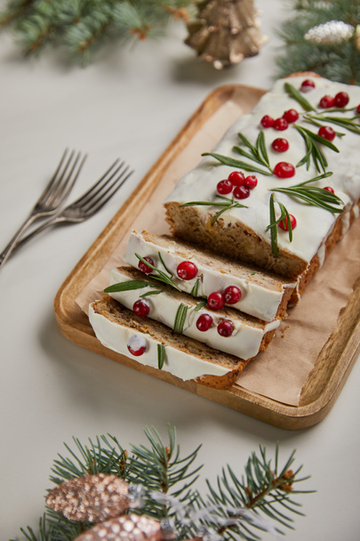 gâteau de Noël traditionnel avec canneberge près des fourchettes, des boules et du pin sur table blanche
 - Photo, image