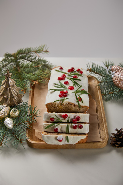 traditionele kersttaart met cranberry in de buurt van kerstballen en dennen op witte tafel geïsoleerd op grijs - Foto, afbeelding
