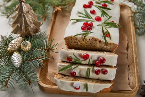 traditional Christmas cake with cranberry near baubles and pine on white table - Foto, immagini