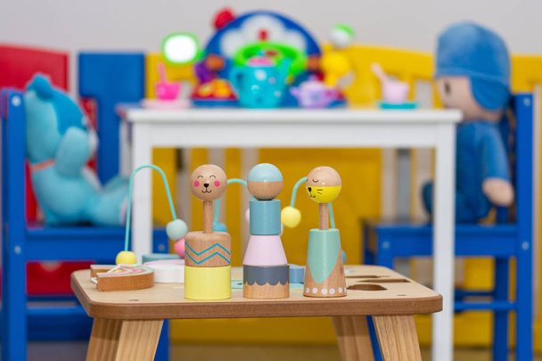 madrid, spanien; 11 / 07 / 2019: hölzerner Spieltisch mit passenden Stücken und Puppen im Hintergrund mit einem Tisch mit Spielzeugbechern - Foto, Bild
