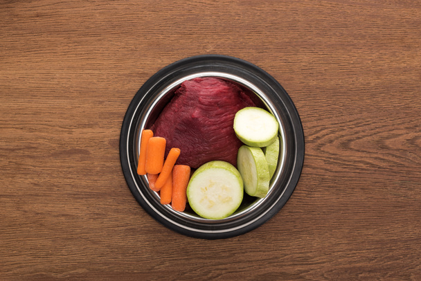 top view of raw vegetables and meat in bowl on wooden table - Foto, Imagen