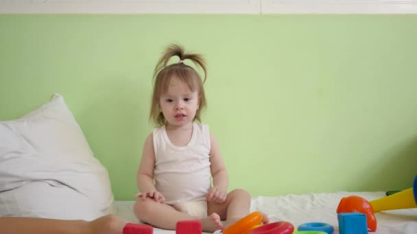 enfant joue avec des cubes multicolores sur un lit blanc et les jette à sa mère. Jouets éducatifs pour enfants d'âge préscolaire et maternelle. Jouet pour enfant
. - Séquence, vidéo