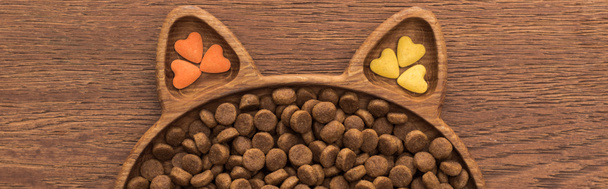 ylhäältä näkymä kissan kuivaa lemmikkieläinten ruokaa ja vitamiineja kissan muotoinen levy puinen pöytä, panoraama laukaus
 - Valokuva, kuva