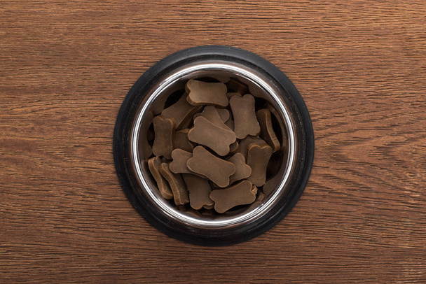 vista superior de comida seca para mascotas en un tazón de plata sobre una mesa de madera
 - Foto, Imagen