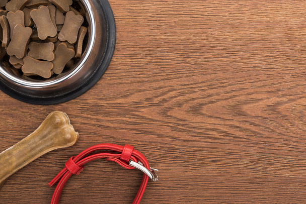 top view of dry pet food in silver bowl near bone, collar on wooden table - Photo, Image