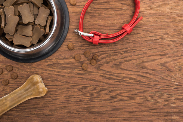 top view of dry pet food in silver bowl near bone, collar on wooden table - Photo, Image