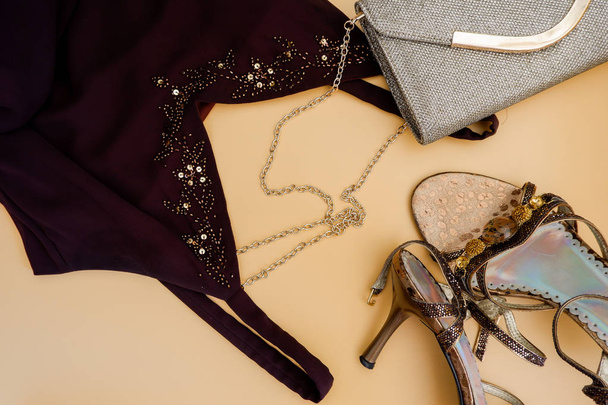 Fashion flat lag. Formele avondkleding: bruine jurk, gouden kettingzak, hoge hakken - Foto, afbeelding