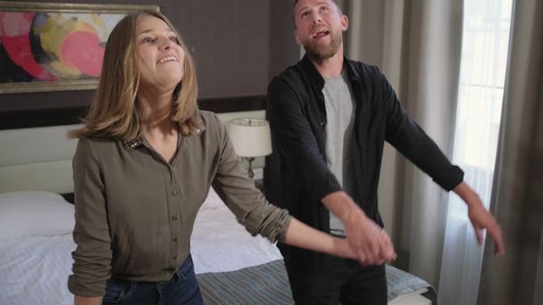 loving pair is falling on bed in hotel room - Filmati, video