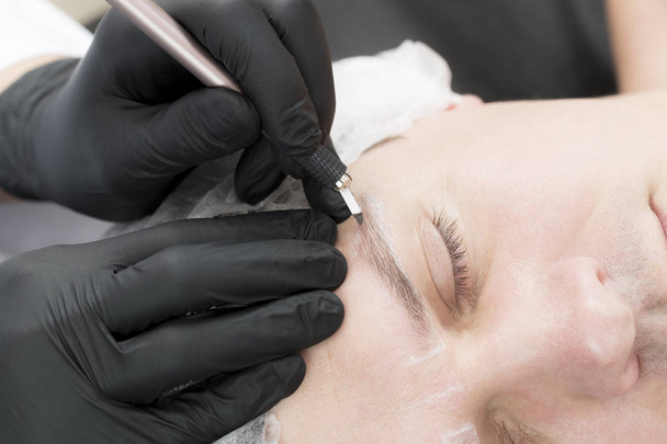 Microblading procedura del tatuaggio del sopracciglio in un salone di bellezza per gli uomini
 - Foto, immagini
