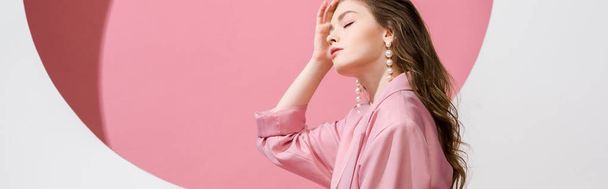 panoramic shot of beautiful girl touching hair on white and pink  - Fotoğraf, Görsel