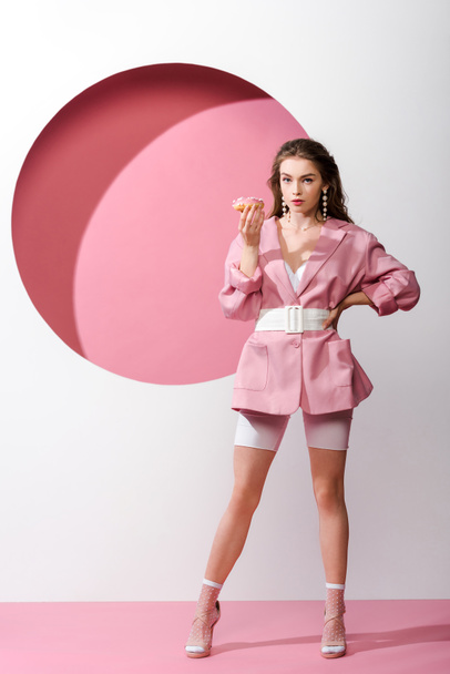 houkutteleva nainen seisoo käsi lonkalla ja tilalla makea donitsi valkoinen ja vaaleanpunainen
  - Valokuva, kuva