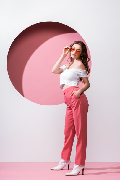 belle fille touchant lunettes de soleil sur blanc et rose
  - Photo, image