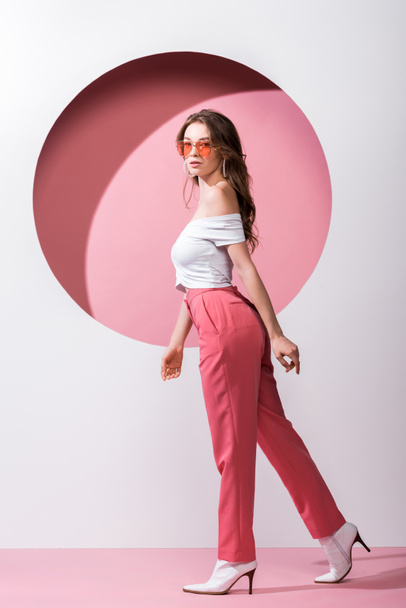 belle fille en lunettes de soleil marchant sur blanc et rose
  - Photo, image