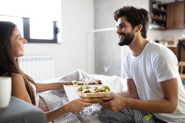 Care and romance at the morning. Happy young couple have breakfast at the bed - Fotoğraf, Görsel