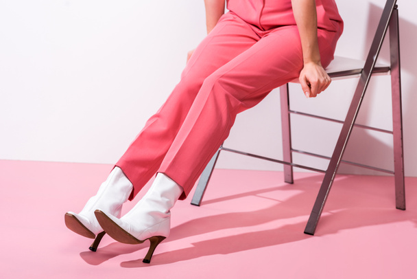cropped view of woman in boots sitting on white and pink  - Foto, Imagen