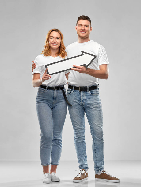 happy couple in white t-shirts with arrow to right - Φωτογραφία, εικόνα