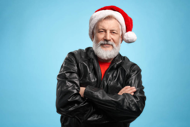 Elder man with grey beard in Santa hat and black jacket - 写真・画像