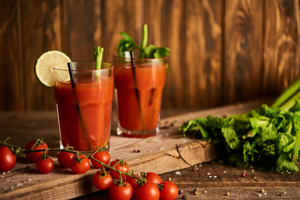 bloody mary cocktail in glasses on wooden background with salt, pepper, tomatoes and celery - Photo, Image