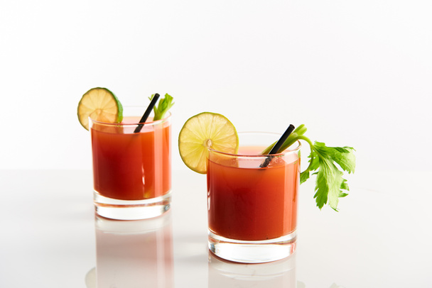 bloody mary cocktail in glasses garnished with lime and celery isolated on white - Photo, Image