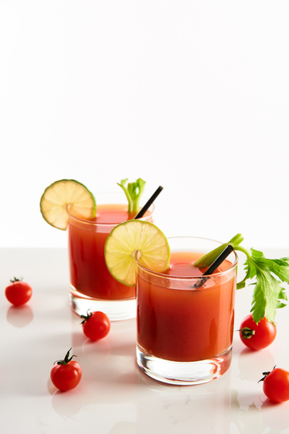 Bloody Mary koktejl v brýlích zdobené vápnem a celer izolované na bílém s rajčaty - Fotografie, Obrázek