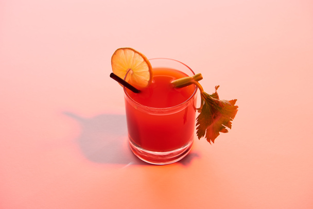 blutiger Mary-Cocktail im Glas garniert mit Limette und Sellerie auf rot beleuchtetem Hintergrund - Foto, Bild